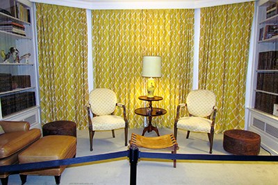 The furniture and curtains in a small sitting room are decorated in the predominate color yellow.