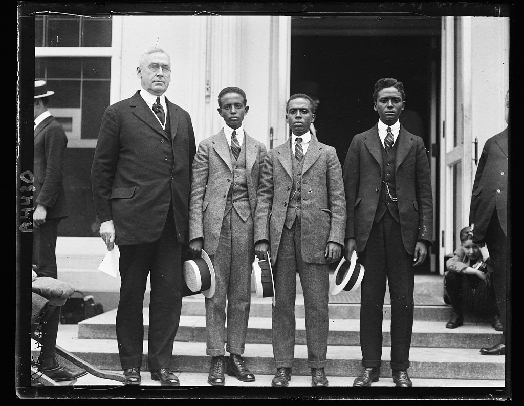 A White American and group of 3 African American Men standing on the steps of the White House.