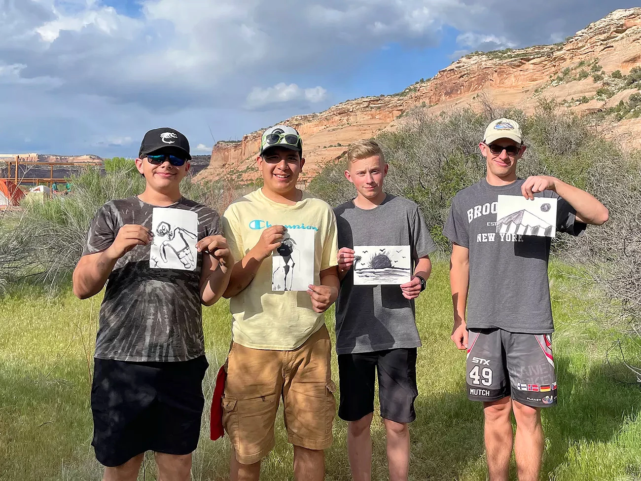 Young citizen scientists Four students outside holding up sketches of outdoor subjects
