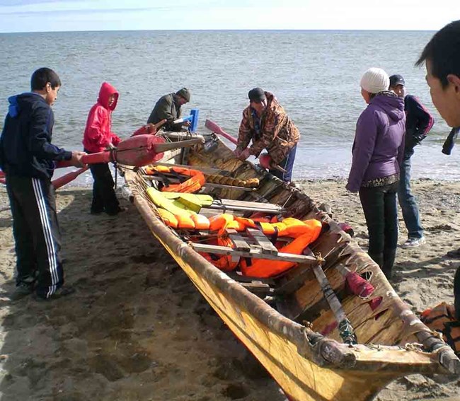 Youth gather around a traditional boat to launch it.