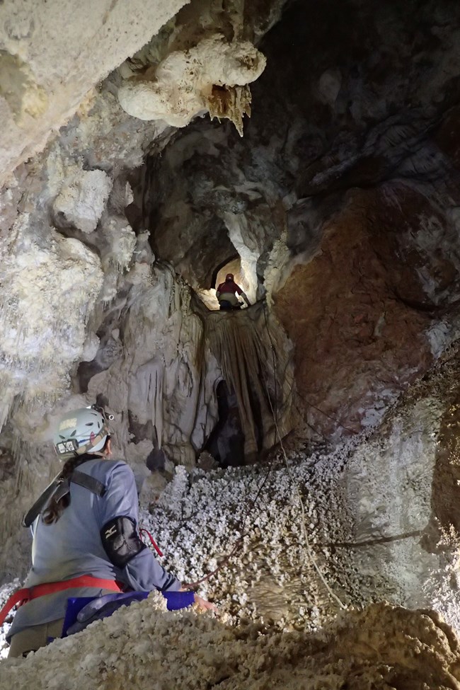 Yvonne Droms belaying Mark Minton at climb above sea-turtle rock (Bob Alderson) a person belaying a climber in a cave