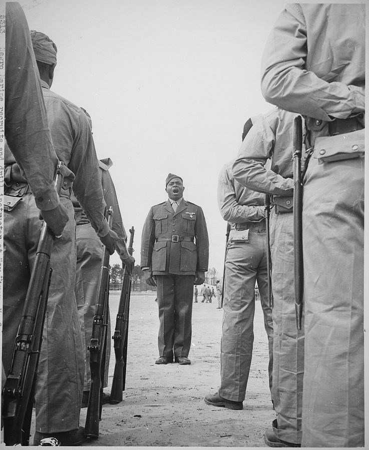 Boot recruits facing towards the drill instructor in the middle of the photograph.