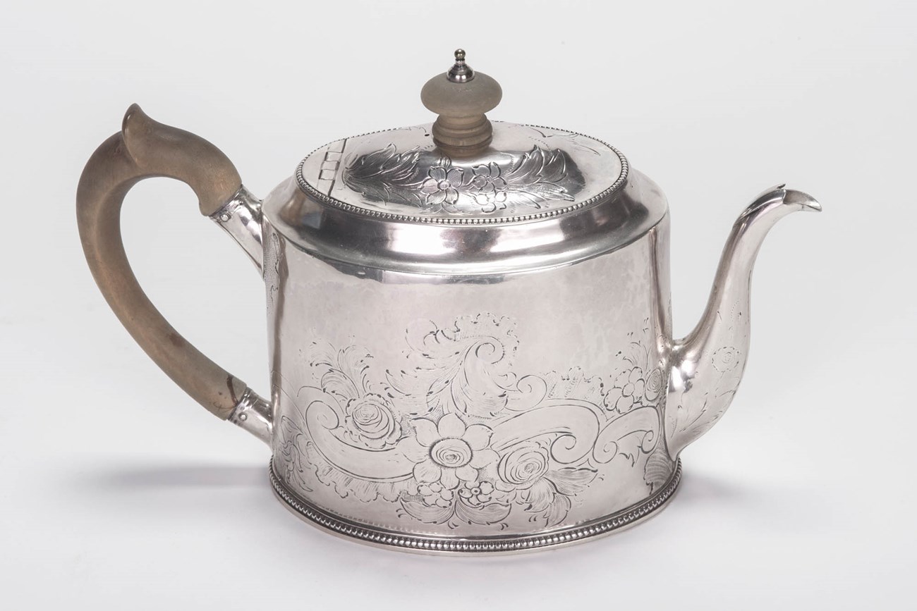 lt= A silver teapot with wood handle.
