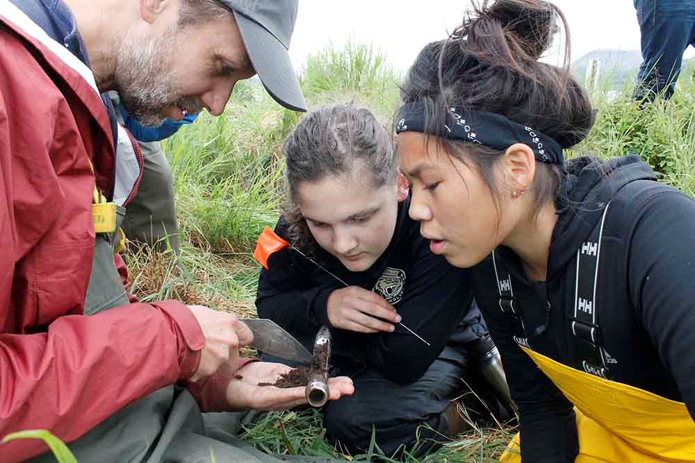 An archaeologist shows kids a soil core.