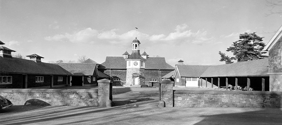 A shingled building complex surrounding a two-story clock tower.