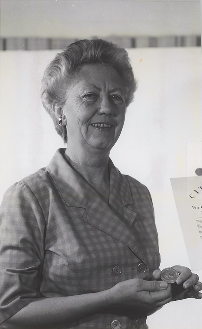 Sallie Harris holding a small round medallion in her hands.