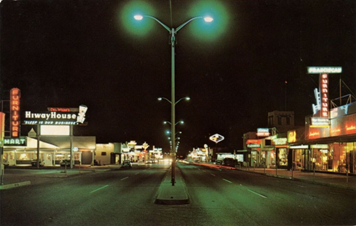 A roadway at night, lined with buildings with neon signs.
