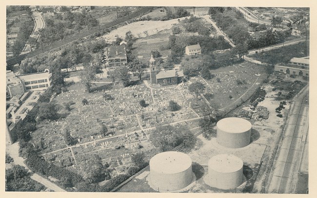 aerialchurchcem1930s Black and white aerial photo, shows cemetery with many gravestones, and adjacent industrial buildings