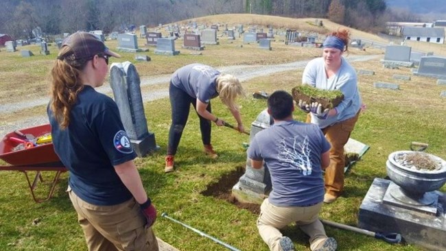 Appalachian Forest NHA Four people perform conservation work, digging out a tract of land in a cemetery