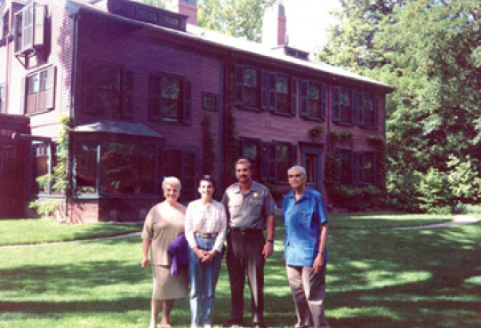 alan Four people stand on large grassy area in front of large home