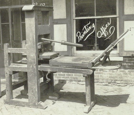 A wooden printing press in front of shop front.
