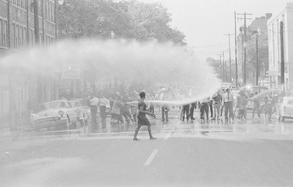 Historical image of police spraying fire houses at demonstrators