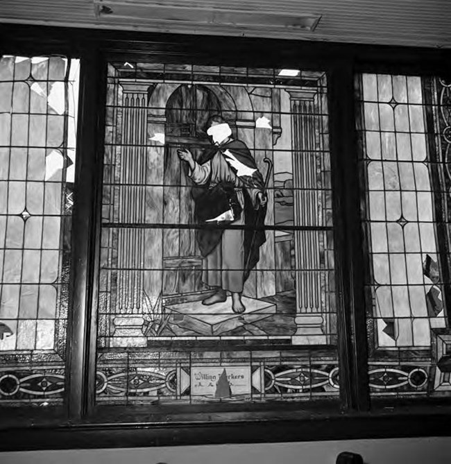 Historic black and white photo of a religious stained glass window broken after a bomb blast