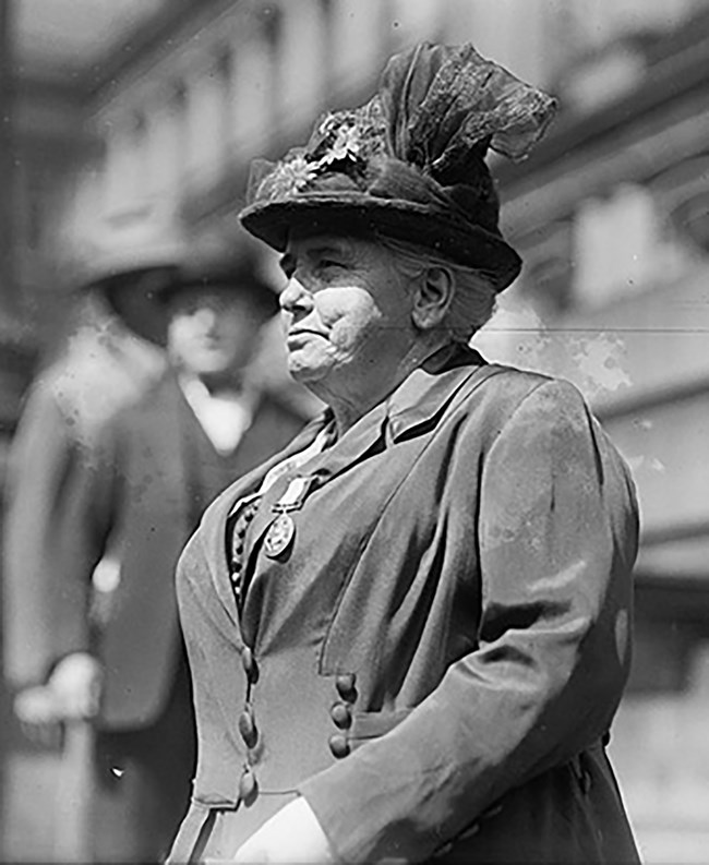 Anna Howard Shaw wearing a hat standing outside LOC