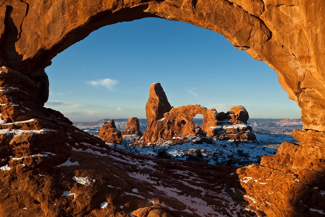 Arches a rock arch frames another rock formation dusted with snow