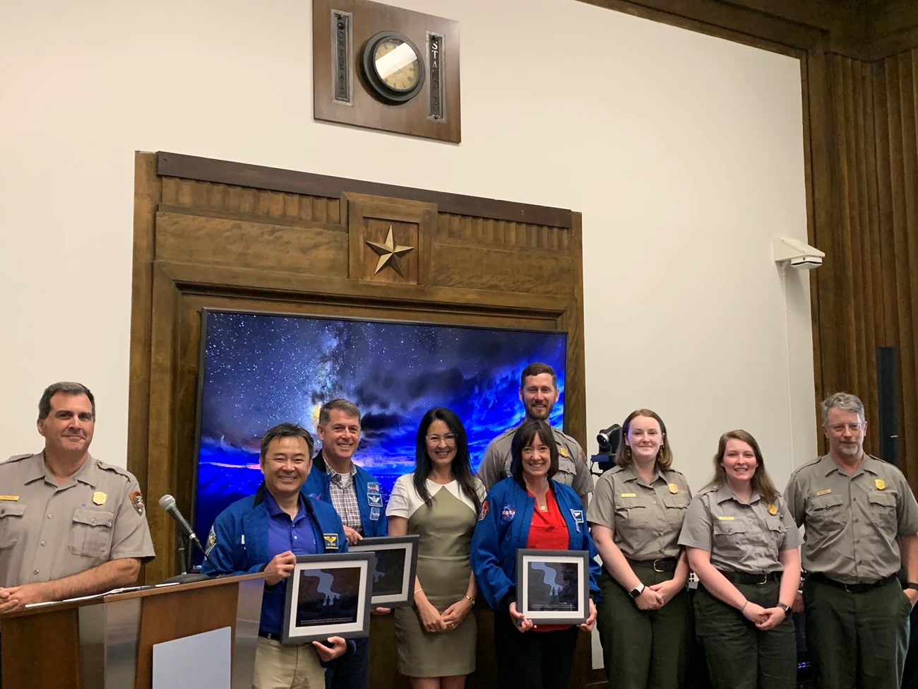 Astronauts and rangers pose together holding plaques. Astronauts and rangers pose together holding plaques.