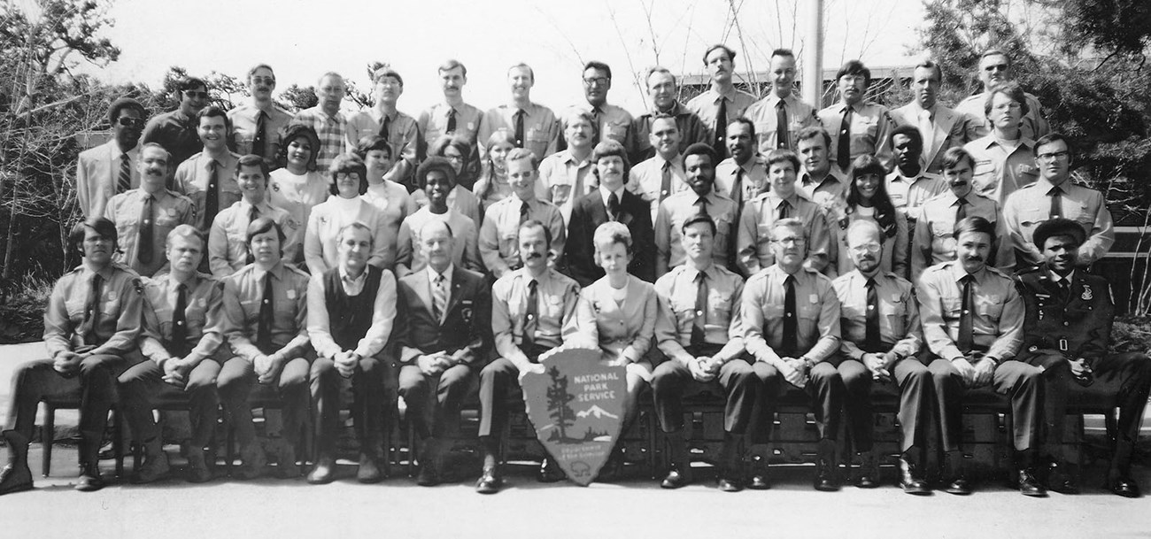 NPS introduction to park operations class, 1974 Park Service employees arranged in four rows pose for a class photo. Most wear NPS uniforms although some are dressed in street clothes.