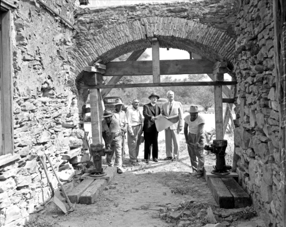 Black and white photo of construction workers and architects at a construction site at Mission Espada