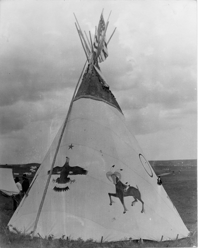 a black and white photograph shows a tipi decorated with hand painted images of animals