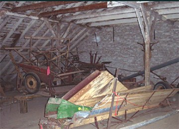 Top floor of barn showing historic farm machinery being stored.