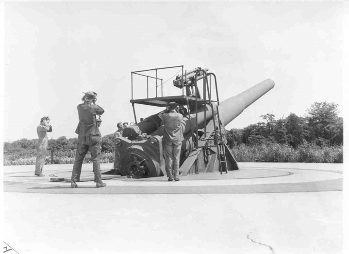 three uniformed men stand around a historic battery