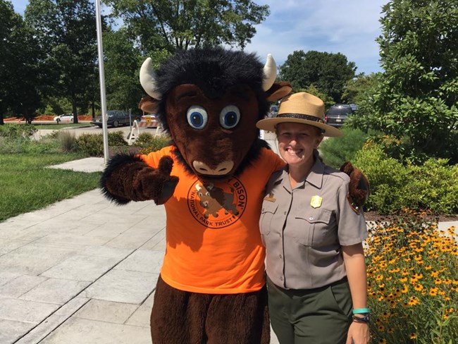 A park ranger takes a photo with a bison mascot.