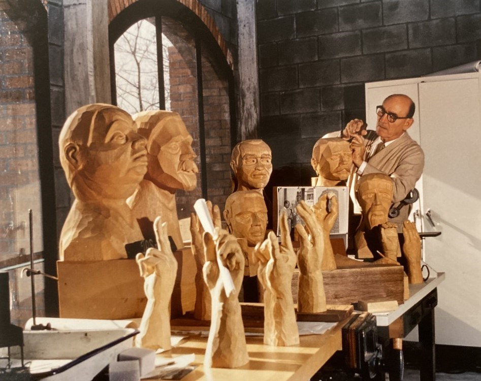 Carved wooden busts and hands on a table in front of John Segeren.