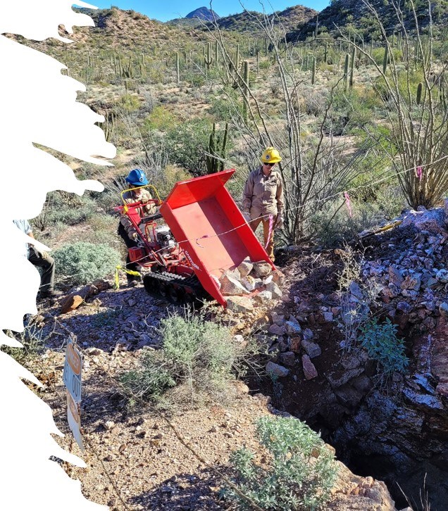 Senita Basin Mine a crew of people in hard hats use heavy machinery to fille in a hazard mine site in the desert