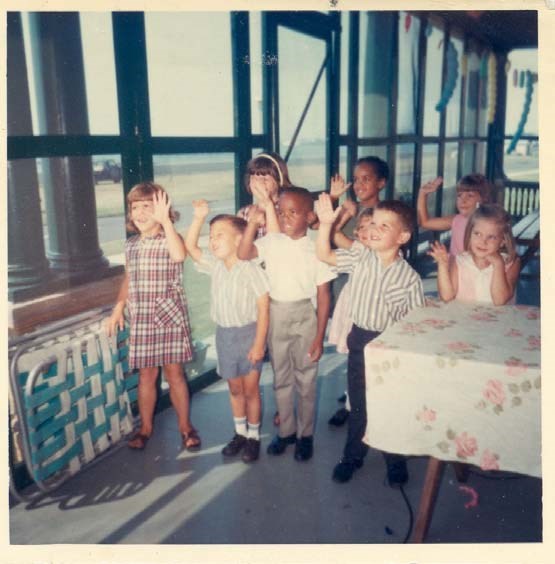 a group of children stand together all raising their hands