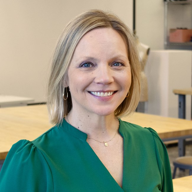 Rachel Black A woman with short, blonde hair smiles in a classroom.