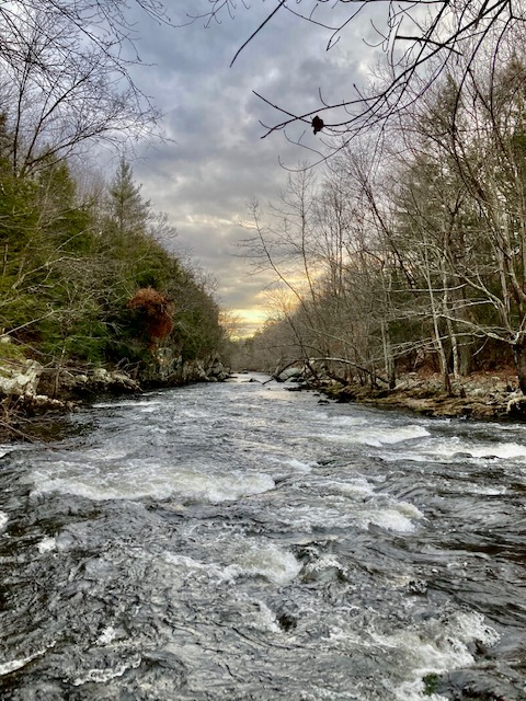 Blackstone River Gorge Coursing river with wooded banks. Sunset over horizon above river.