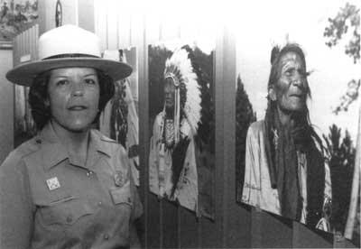 Barbara Booher in her NPS uniform stands in front of an exhibit.