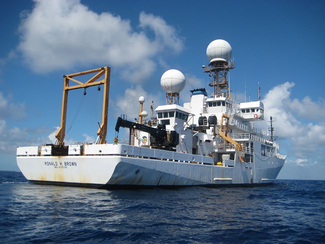 Large white ship with several decks and lots of scientific equipment, off the starboard stern taken from the ship’s workboat.