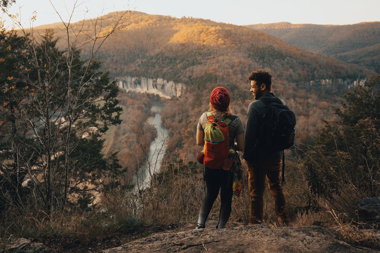 Buffalo National River Wilderness two people stand at the edge of a cliff overlooking a forest and river