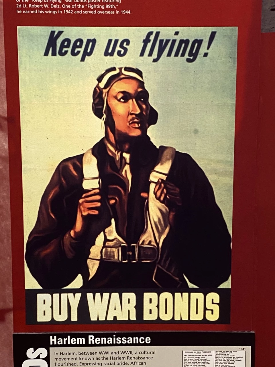 A 1942 WWII propaganda poster on display at Tuskegee Airmen National Historic Site featuring a Tuskegee Airman WWII propaganda poster. "Keep us fling! BUY WAR BONDS"