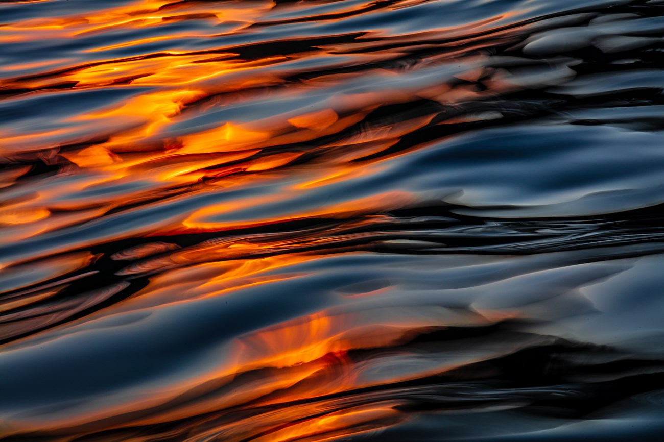Dark, wavy water with orange light reflections.