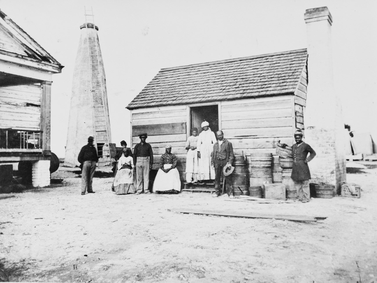 A group of Black men and women standing in front of a cabin.