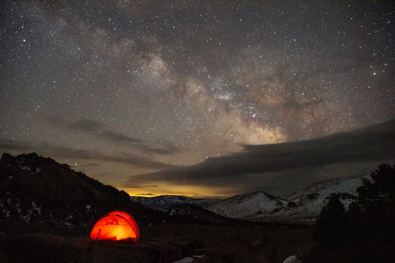 a red tent lit up under the milky way