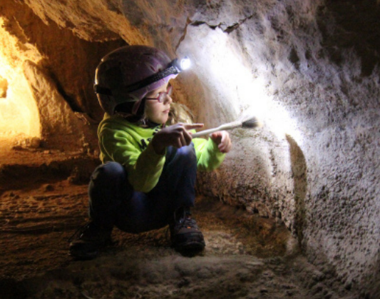 A youth volunteer wiping lint off of the cave wall.