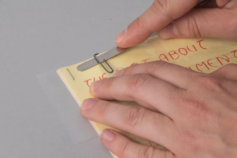 Demonstrating the removal of a paperclip. Demonstrating how to remove a metal paperclip.