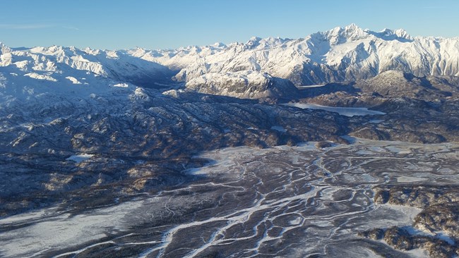 snow capped mountains with a braided river valley