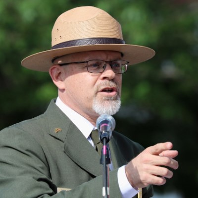 A recent photo of Tom Medema behind a microphone wearing his ranger uniform.