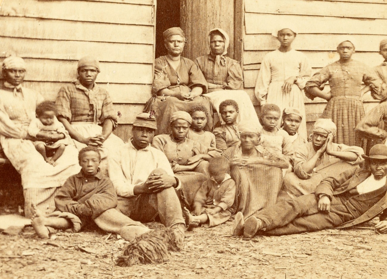 a group of slaves including men, women and children gathered outside a building at the Foller Plantation in Cumberland Landing, Pamunkey Run, Virginia