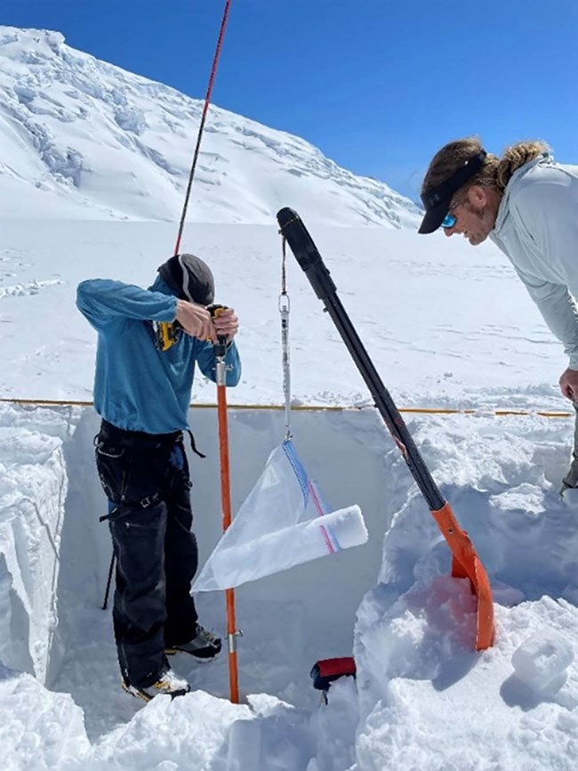 two researchers extract an ice core from a glacier