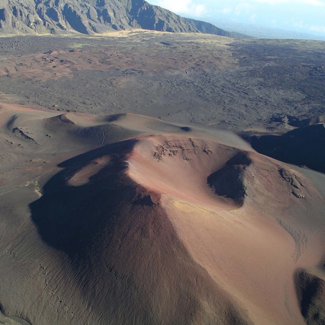 aerial photo of a cinder cone with an expansive volcanic field in the distance