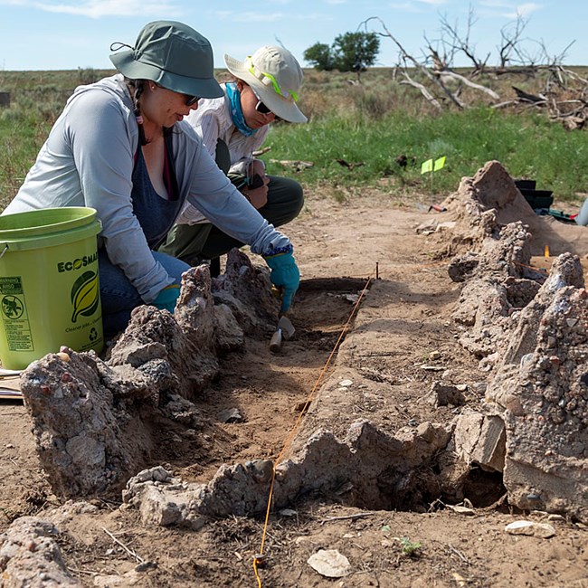 Two people examine a garden feature at amache