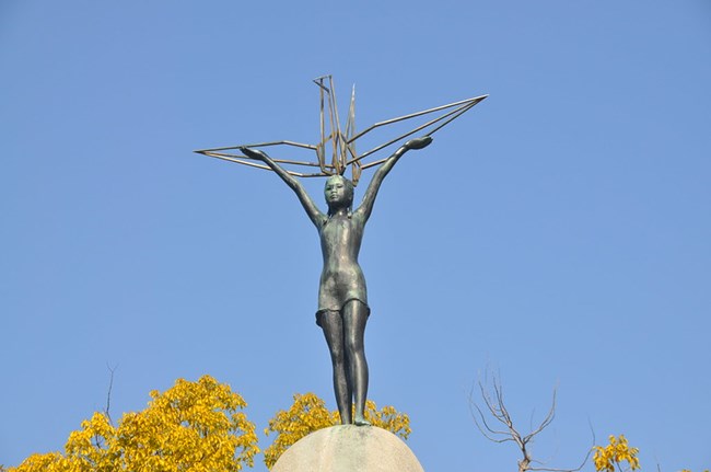 Color photo of statue of child holding origami crane