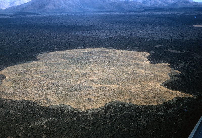 aerial photo of a area of older rock surrounded by a more recent lava flow