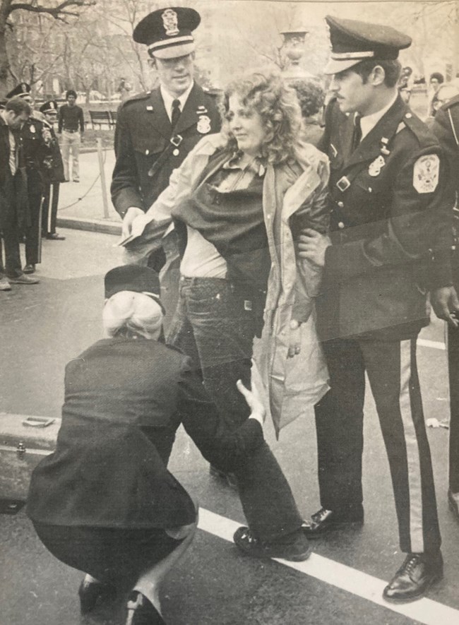 Officer Dabbs searches a woman being held by two male officers.