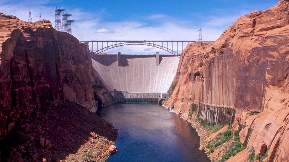 Glen Canyon Dam a river flowing between two cliffs below a concrete dam with a height of 710 feet, and a crest length of 1,560 feet